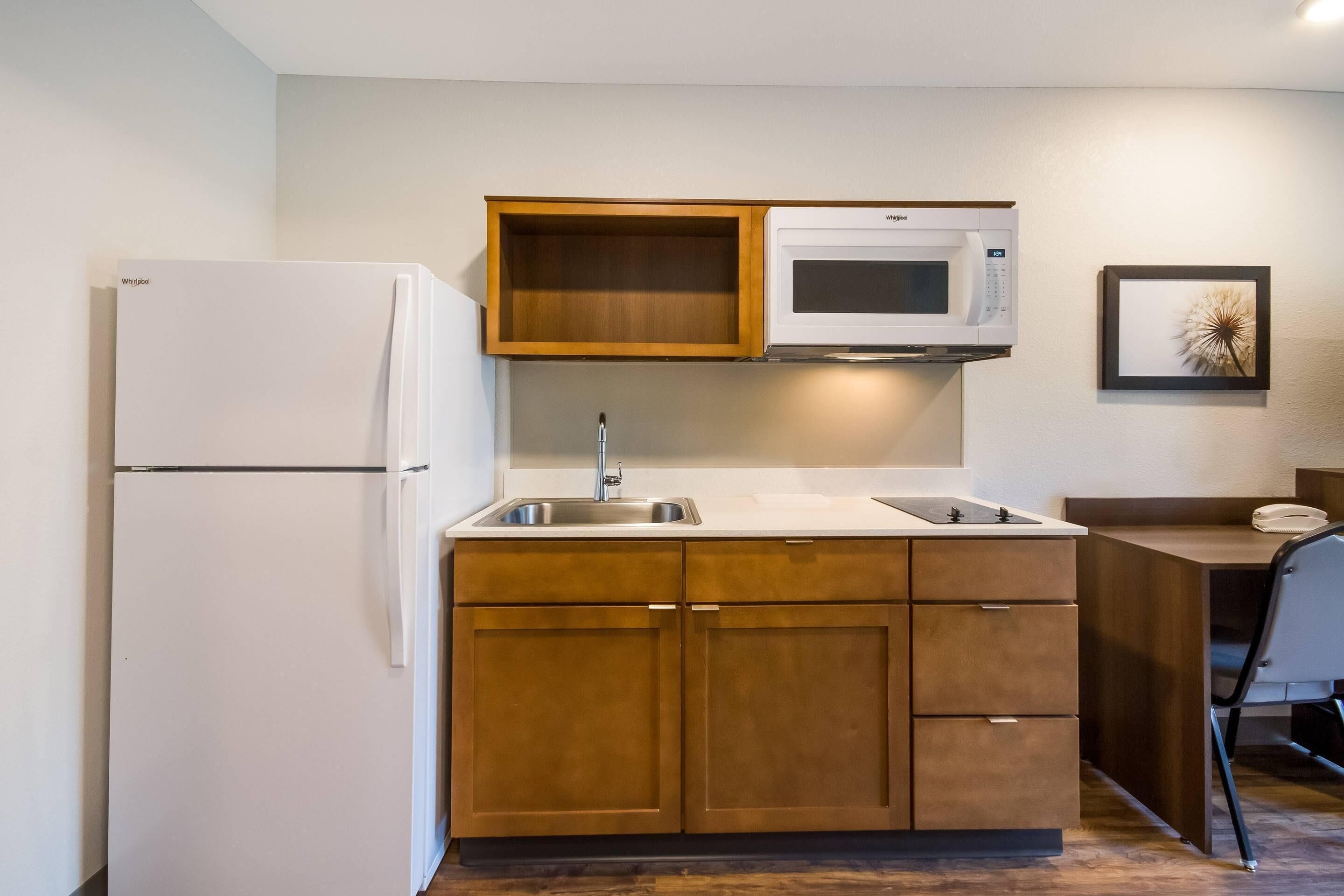 Una cocina compacta con un refrigerador blanco, un microondas y armarios de madera.