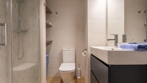 A modern bathroom with a glass-enclosed shower, a toilet, and a sink with a towel. - Atlantis by Interhome (Segur de Calafell)