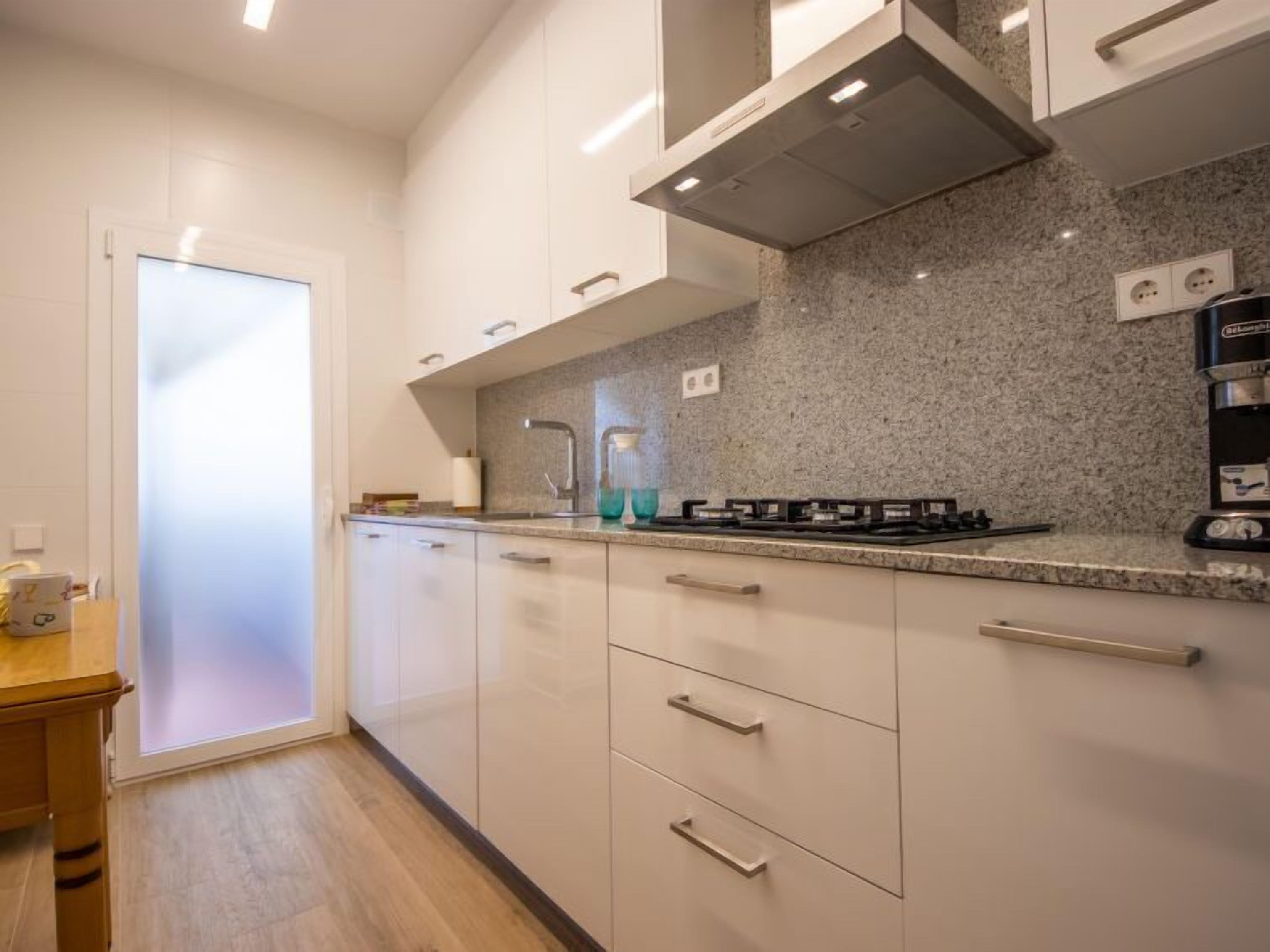 A modern kitchen with white cabinets, granite countertops, and stainless steel appliances.