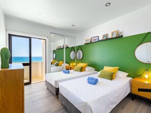 A hotel room with two beds, a green accent wall, a large mirror, and a view of the sea. - Sweet Ocean by Interhome (Armação de Pêra)