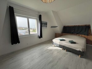 Un dormitorio con cama, ventana y vistas al exterior.