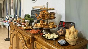 Una mesa de bufé con diversos alimentos, como pasteles, quesos y pan.