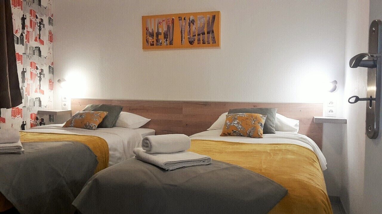 A hotel room with two beds, each with a headboard, a nightstand, and a wall-mounted artwork.