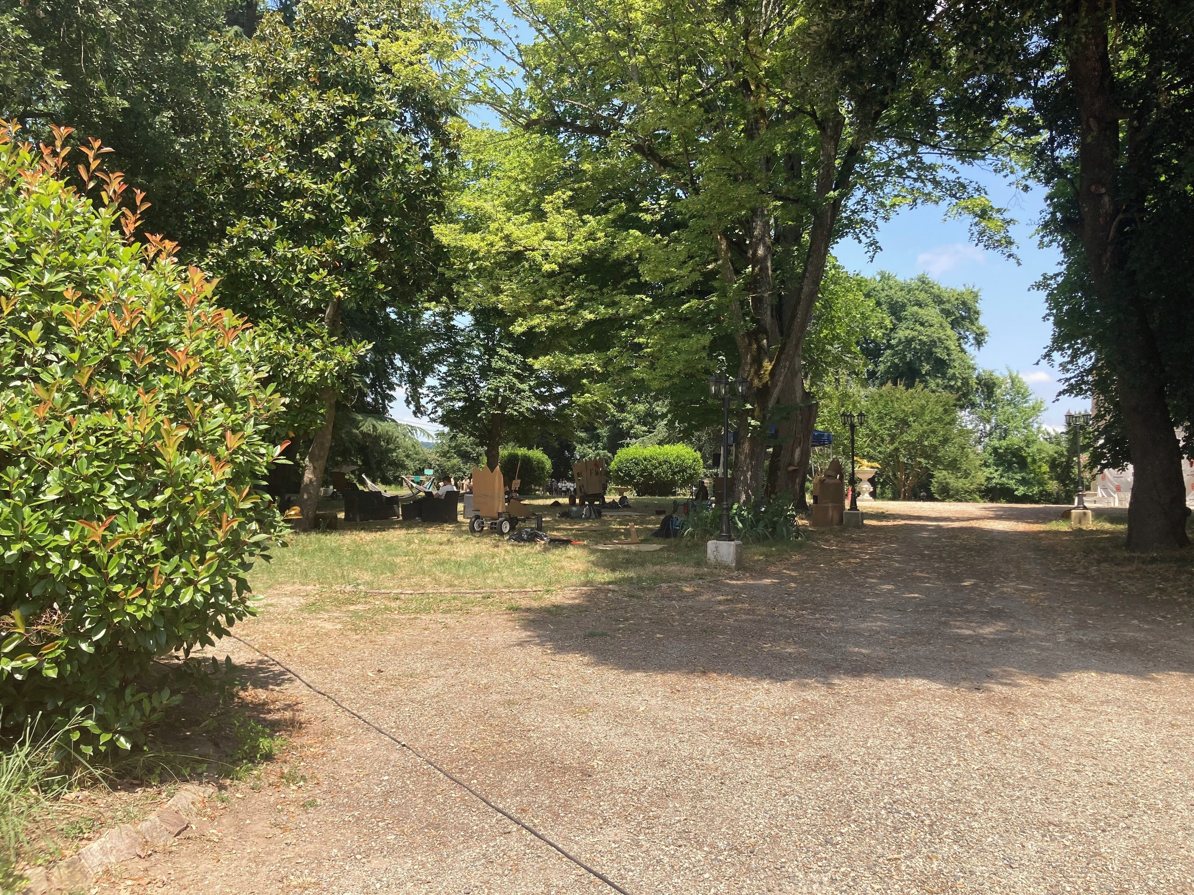 Ein Park mit Bäumen, einem gepflasterten Weg und Sitzgelegenheiten im Freien.