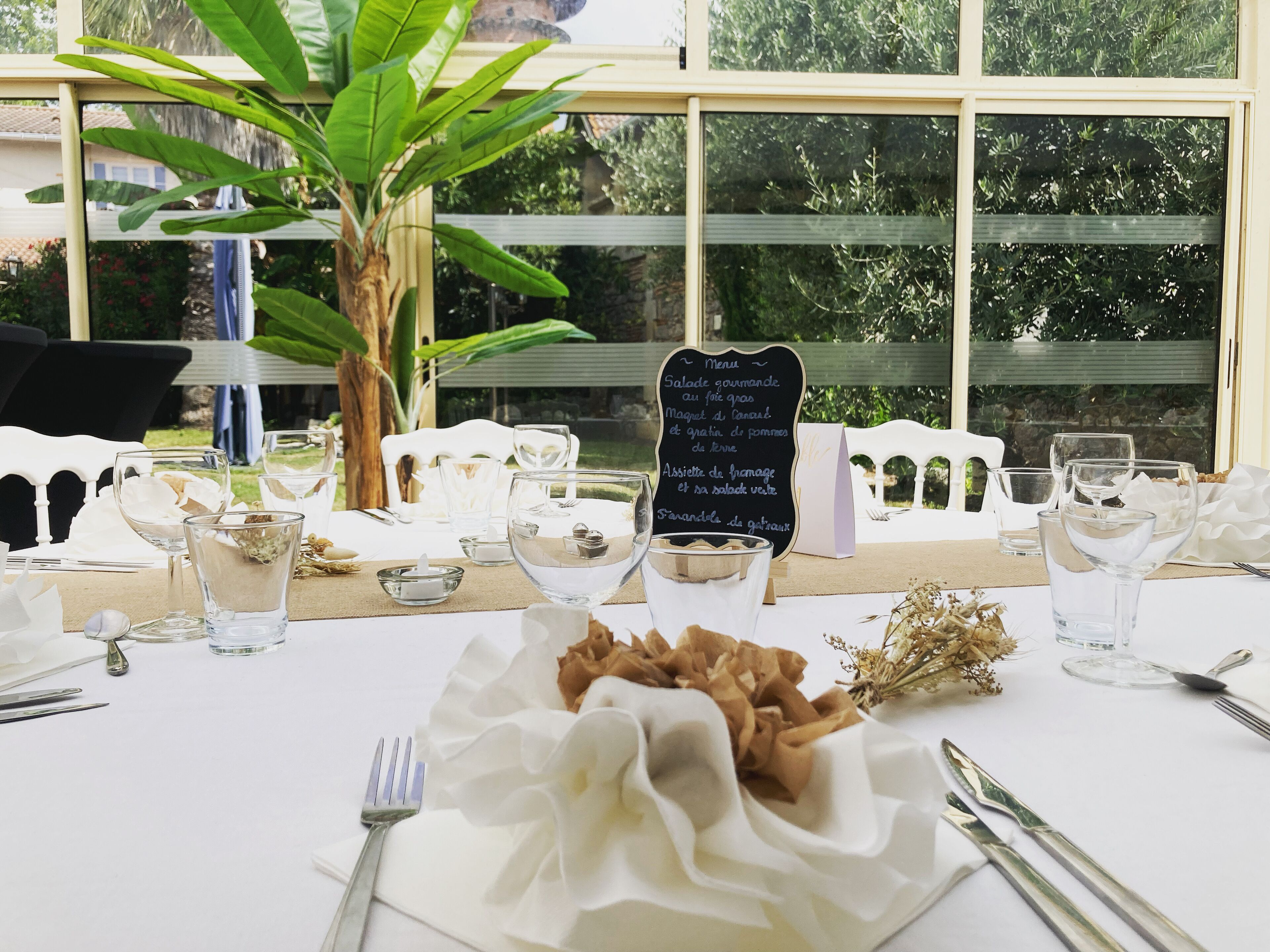 A table set for a meal with a menu sign, clear glassware, and a centerpiece.