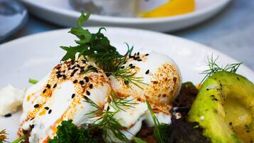 En tallrik med ett pocherat ägg, avokado, grönsaker och ett till pocherat ägg ovanpå en bädd av grönsaker.