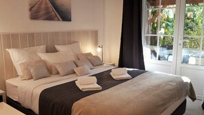 Una cama bien hecha con un cabecero, varias almohadas y toallas dobladas.