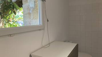 A small, compact bathroom with a toilet, a shower with a curtain, and a window.