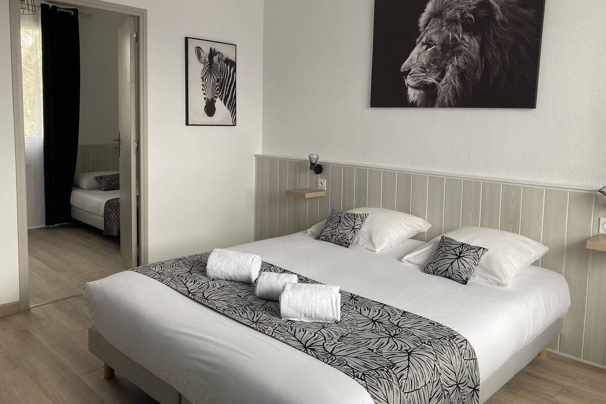 Une chambre moderne avec un grand lit, deux oreillers, une tête de lit et une œuvre d’art représentant un lion, accrochée au mur.
