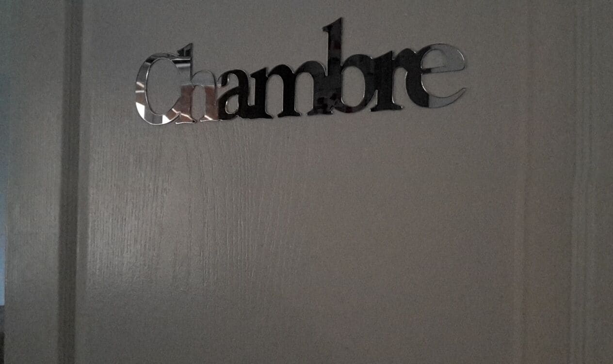 Una señal metálica con la palabra 'Chambre' que indica una habitación u alojamiento.