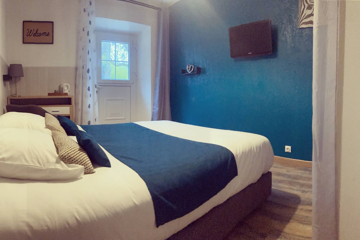 Une chambre à coucher avec un lit, une table de chevet, une lampe, une fenêtre et une porte.