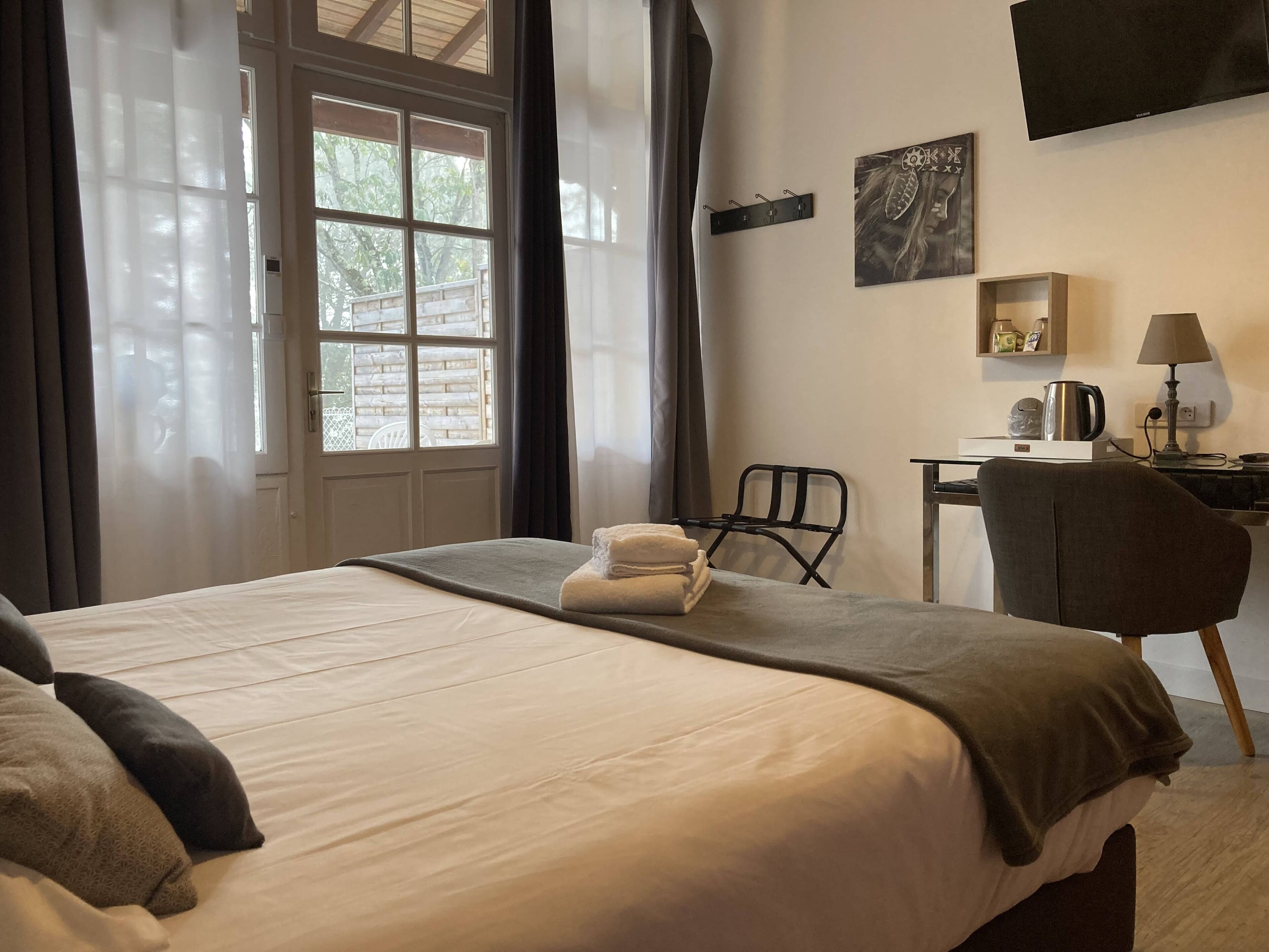 A hotel room with a bed, a desk, a chair, and a window with curtains.