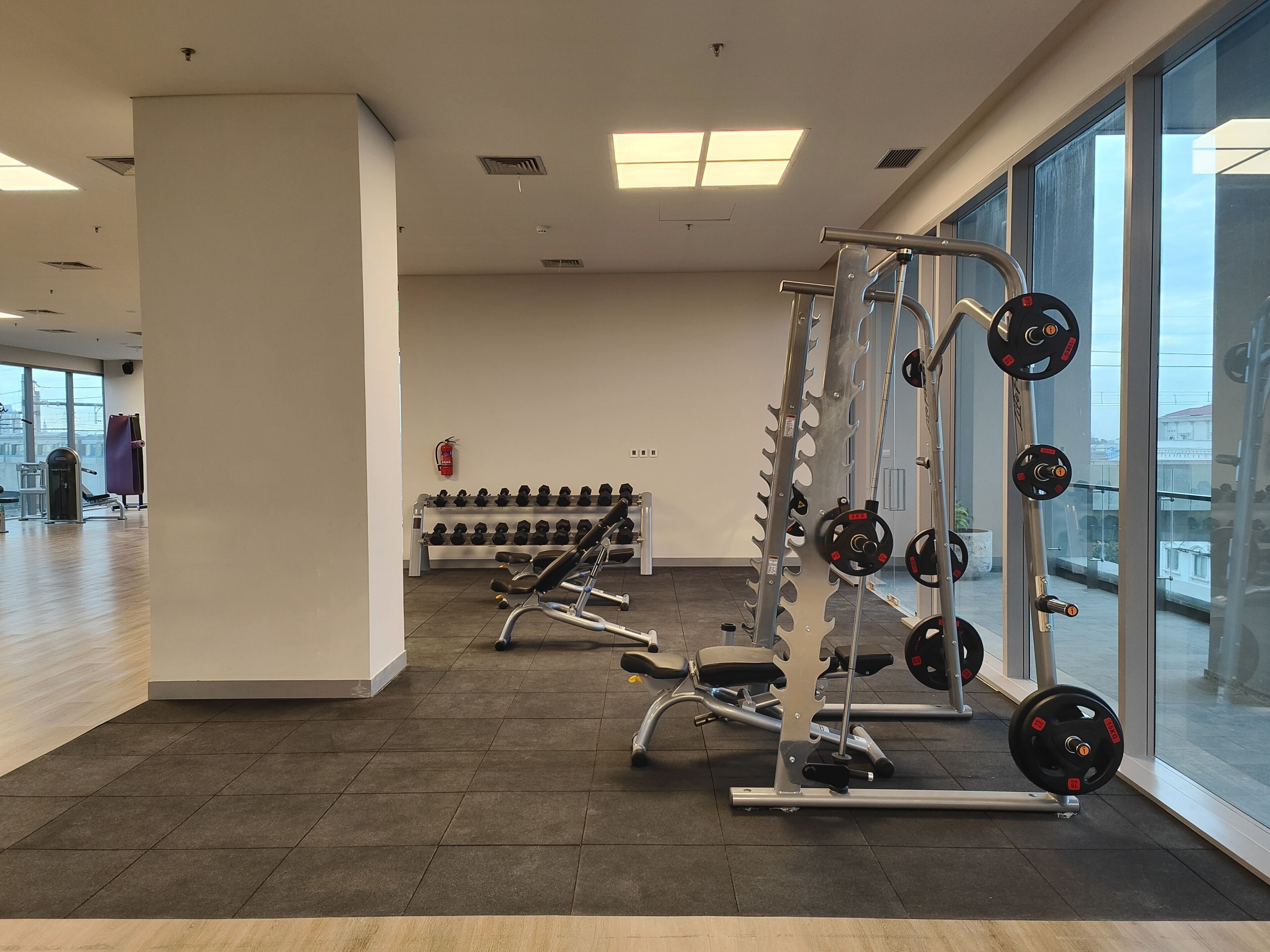 A gym with weightlifting equipment, dumbbells, and a fire extinguisher.