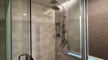 A modern shower with a glass door, a handheld showerhead, and a wall-mounted control panel.
