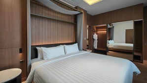 A modern hotel room with a large bed, a walk-in closet, and a mirror. - Ra Suites Simatupang (Jakarta)