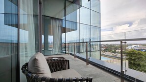 A balcony with a wicker chair and a view of a cityscape. - Ra Suites Simatupang (Jakarta)