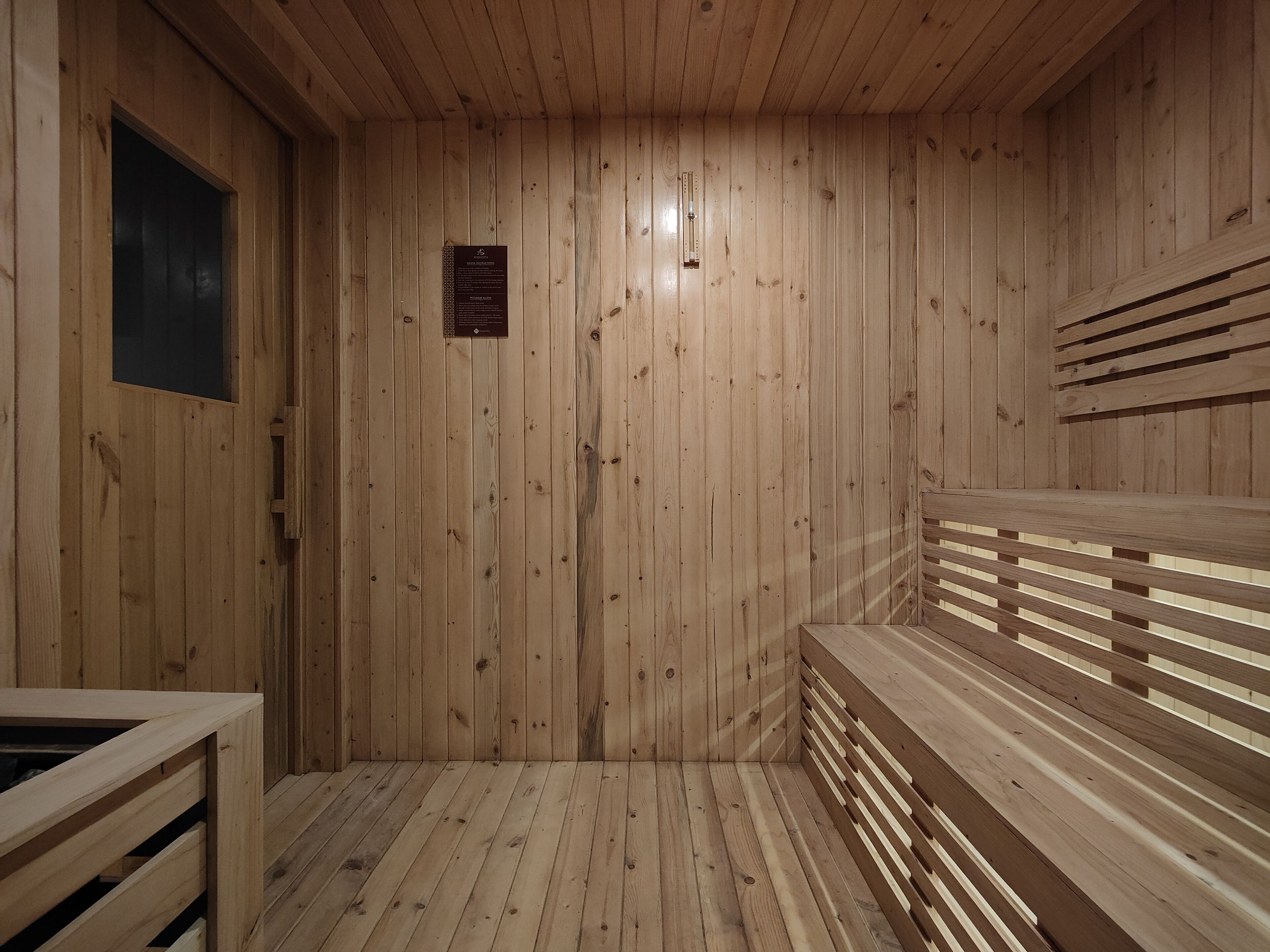 A wooden sauna with benches and a bench with a backrest.