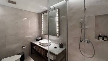 A modern bathroom with a glass-enclosed shower, a white toilet, and a vanity with a mirror.