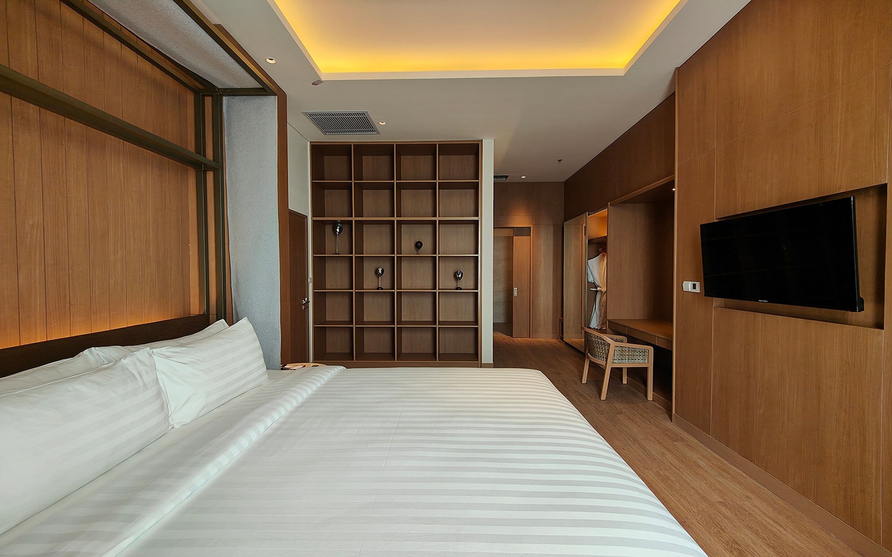 Habitación de hotel con una cama grande, paneles de madera, armario empotrado, televisor y zona de estar.