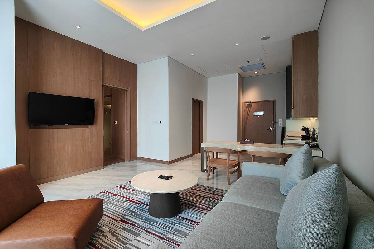 Una sala de estar moderna con un sofá, una mesa de centro y un televisor montado en la pared.