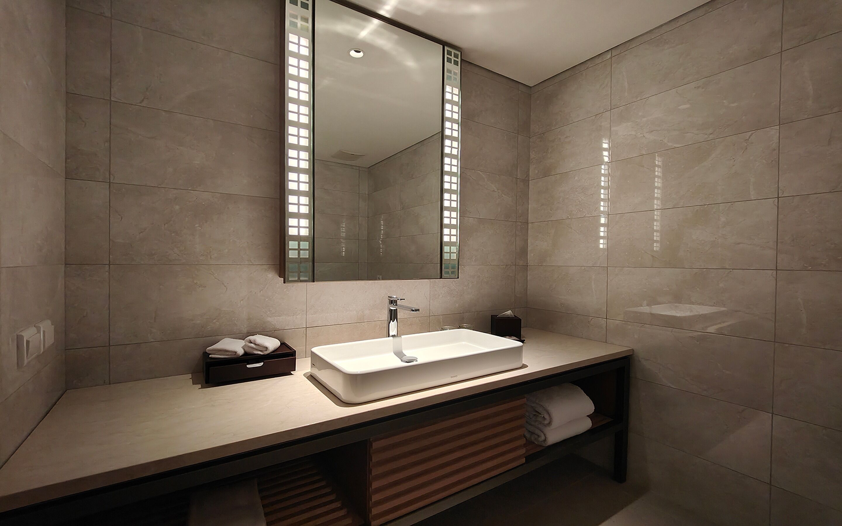 Un baño moderno con un espejo grande, un lavabo blanco y un perchero para toallas.