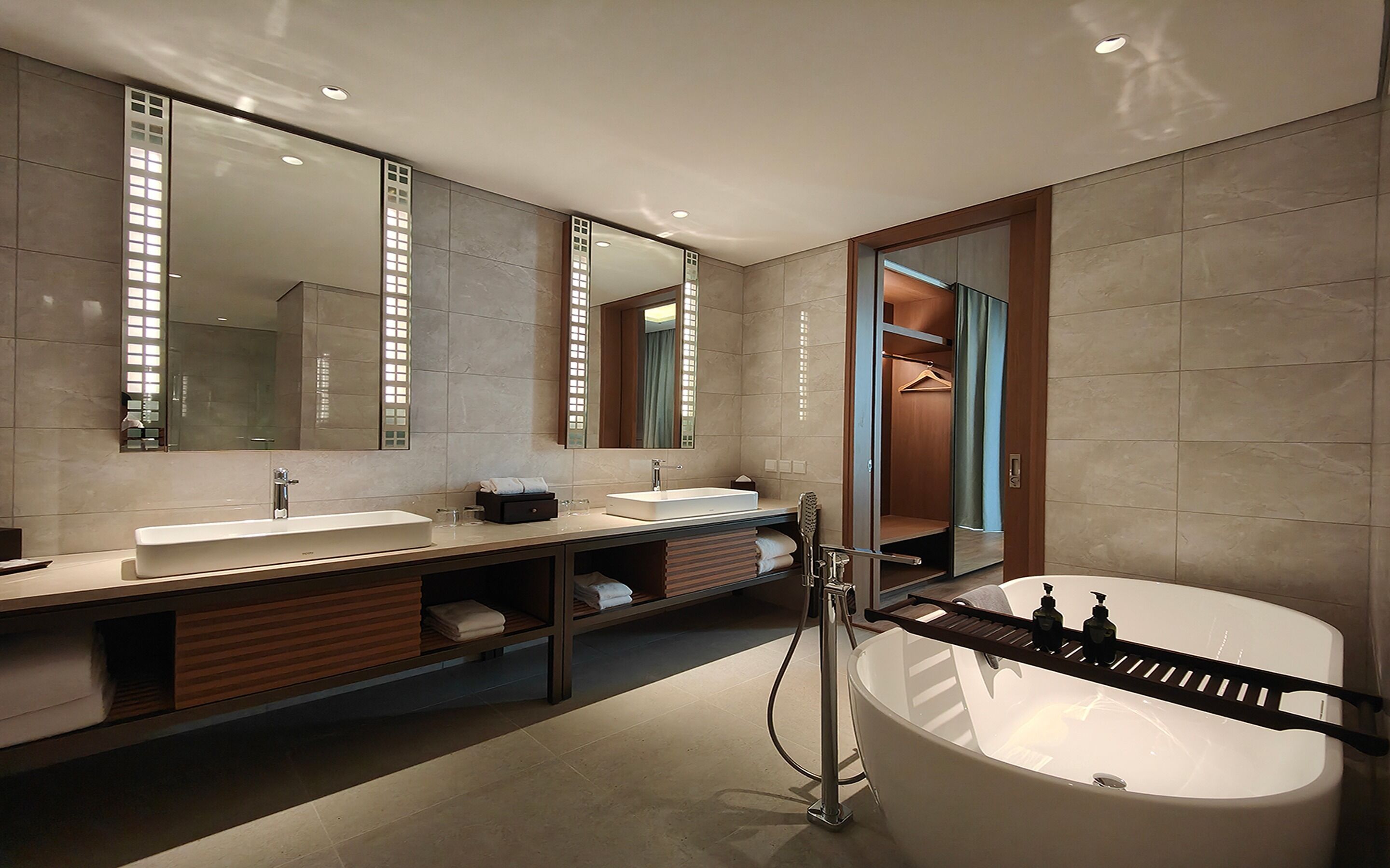 A modern bathroom with two sinks, a large bathtub, and a walk-in shower.