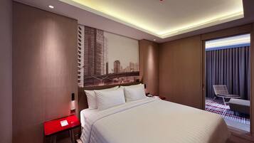 A hotel room with a large bed, a red nightstand, a cityscape mural, and a view of a city through a window.