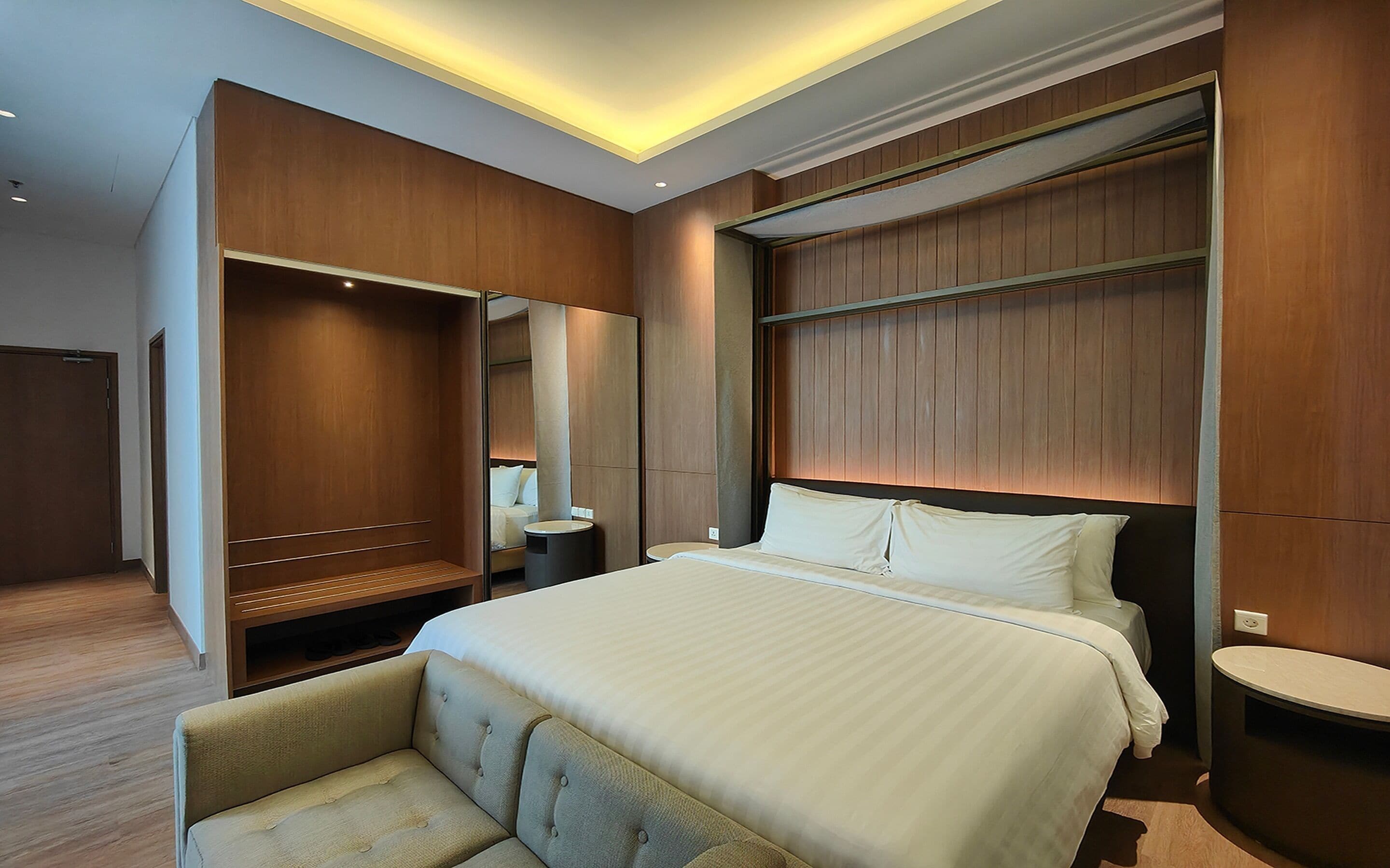A hotel room with a large bed, a seating area, a vanity, and a walk-in closet.