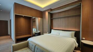 A hotel room with a large bed, a seating area, a vanity, and a walk-in closet.