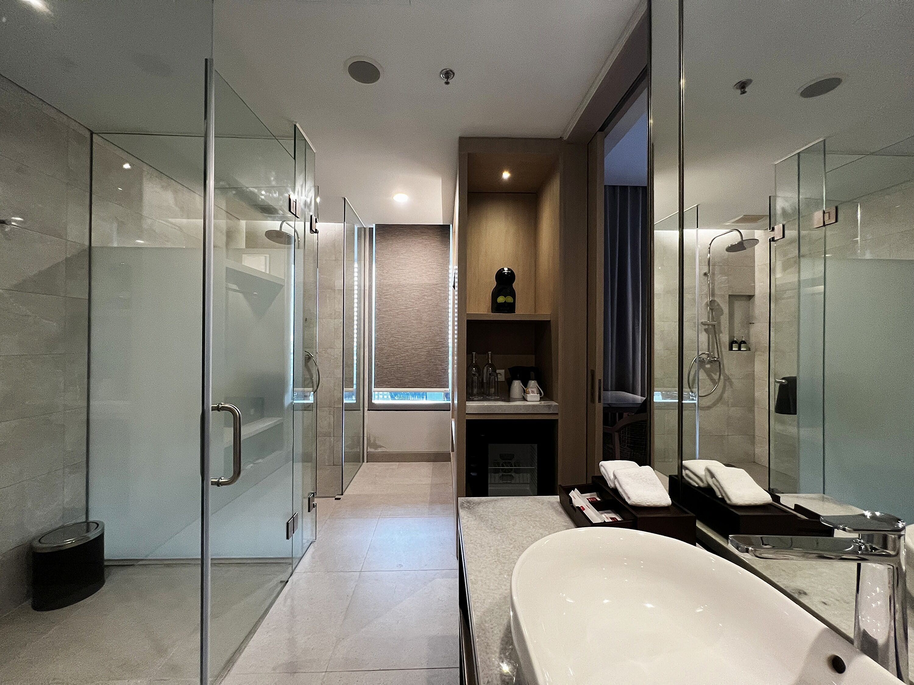 Une salle de bain moderne dotée d’une douche à parois de verre, d’une grande baignoire et d’un meuble-lavabo avec un miroir.