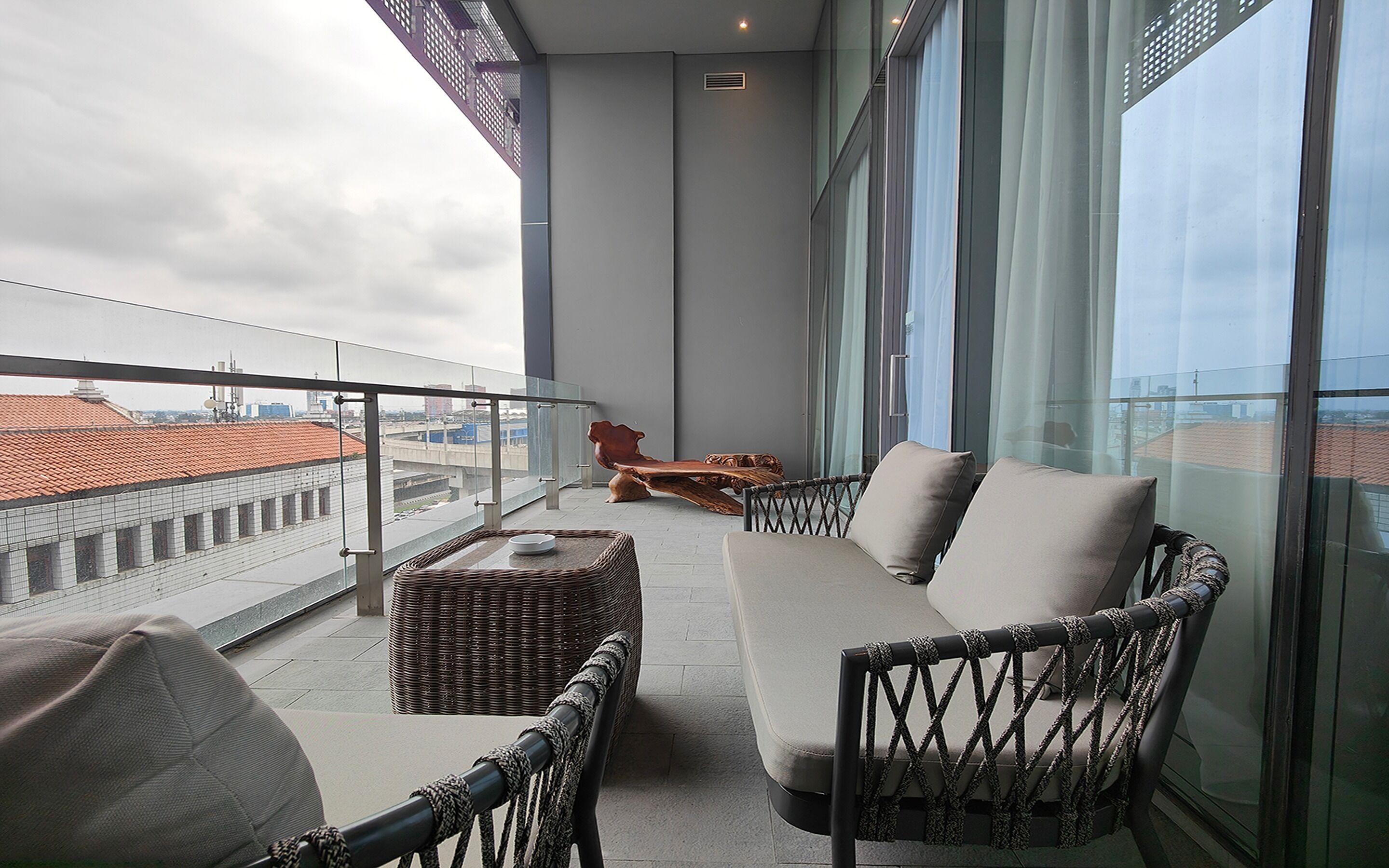 Ein Balkon mit Rattanmöbeln, einer Couch und Blick auf die Stadt.
