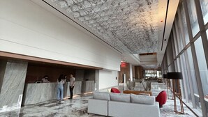 A spacious lobby with a marble floor, a reception desk, a seating area with a sofa and chairs, and large windows allowing natural light. - Ra Suites Simatupang (Jakarta)