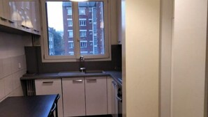 Eine kompakte Küche mit Fenster, einem Esstisch und einer Pendelleuchte.
