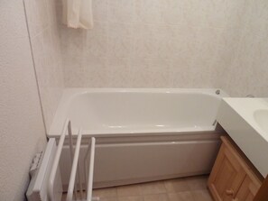 A bathroom with a bathtub, a white towel hanging on the wall, and a wooden cabinet. - 3-Room Cabin Rental - Pets Welcome, Parking - At the Foot of Slopes in St Jean d'Aulps (Saint-Jean-d'Aulps)