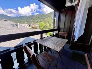 A balcony with a table and chairs, overlooking a residential area and mountains.