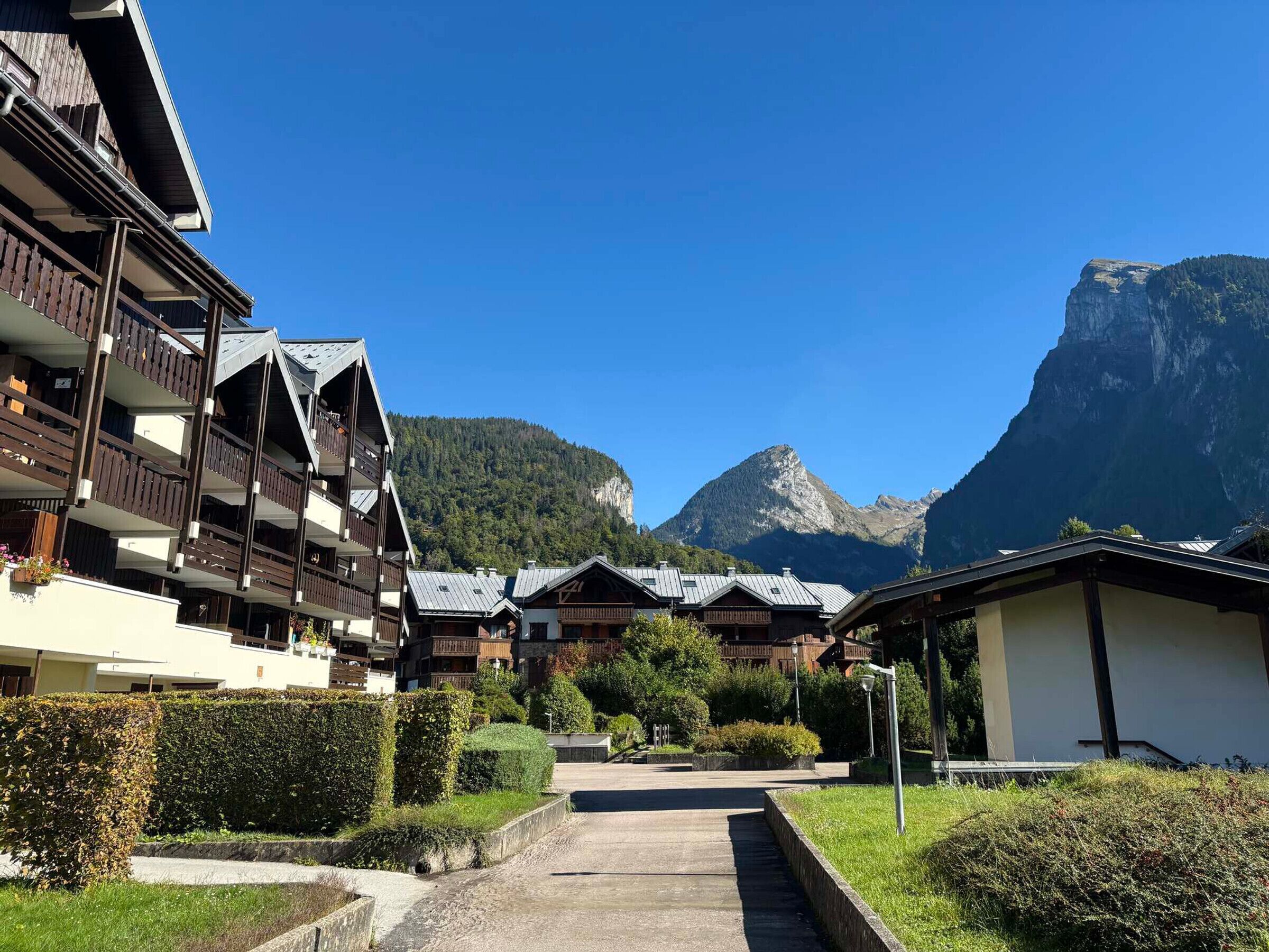 A mountain resort with multi-story buildings, a clear sky, and a prominent mountain in the background.