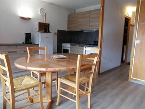Uma cozinha compacta com micro-ondas, cafeteira e um relógio na parede.