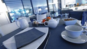 A dining table with a white plate, napkin, and cutlery, a teapot, a cup, and a bowl of snacks. - Park Hotel Sporting (Teramo)