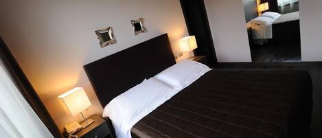 Una habitación de hotel con una cama grande, dos mesitas de noche y un espejo.