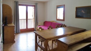 A room with a wooden table and benches, a pink sofa, and a wooden cabinet. - Apartment for 8 with balcony near cable car and shops (Valfréjus)