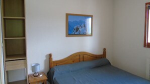A bedroom with a wooden bed, a nightstand, a shelf unit, and a framed picture on the wall. - Apartment for 8 with balcony near cable car and shops (Valfréjus)