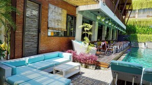 Un área junto a la piscina con un largo banco, un sofá y una mesa.