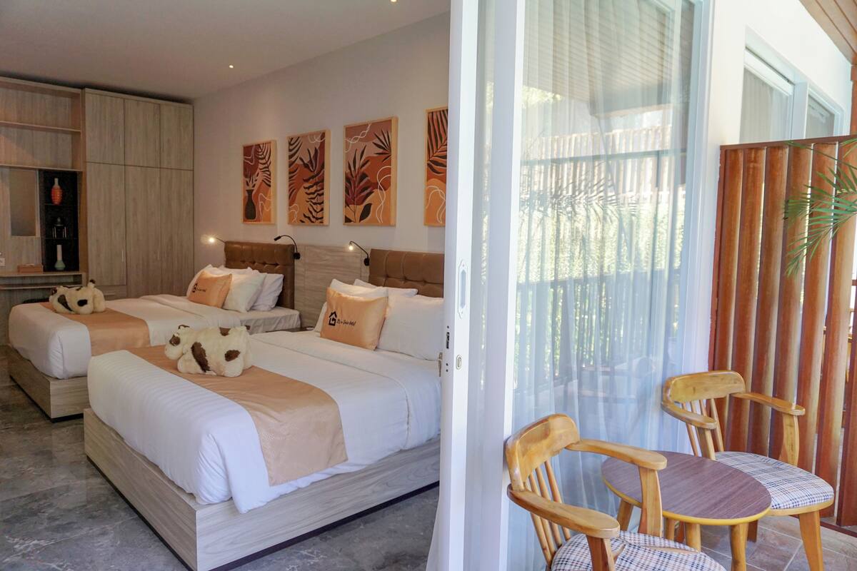 Ein Hotelzimmer mit zwei Betten, einer Sitzecke mit Stühlen und Bildern an den Wänden.