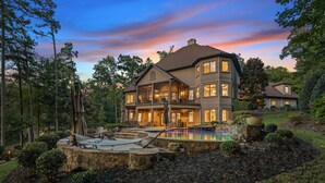 A large, multi-story house with a swimming pool, surrounded by trees and a well-maintained garden.