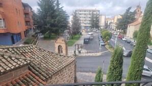A street view with a mix of residential and commercial buildings, a clear road, and a pedestrian crossing. - ELE Mirador de Santa Ana (Ávila)