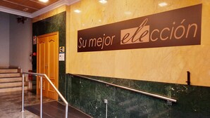 A hotel lobby with a marble staircase, a sign reading "Su mejor elección", and a door with a sign indicating Wi-Fi availability. - ELE Mirador de Santa Ana (Ávila)