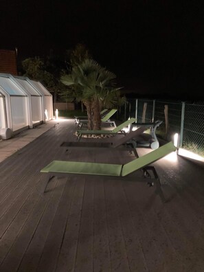 Terraza en la azotea con sillones de descanso y una palmera.