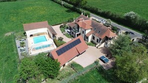 Una casa grande con piscina, paneles solares y entrada para vehículos.