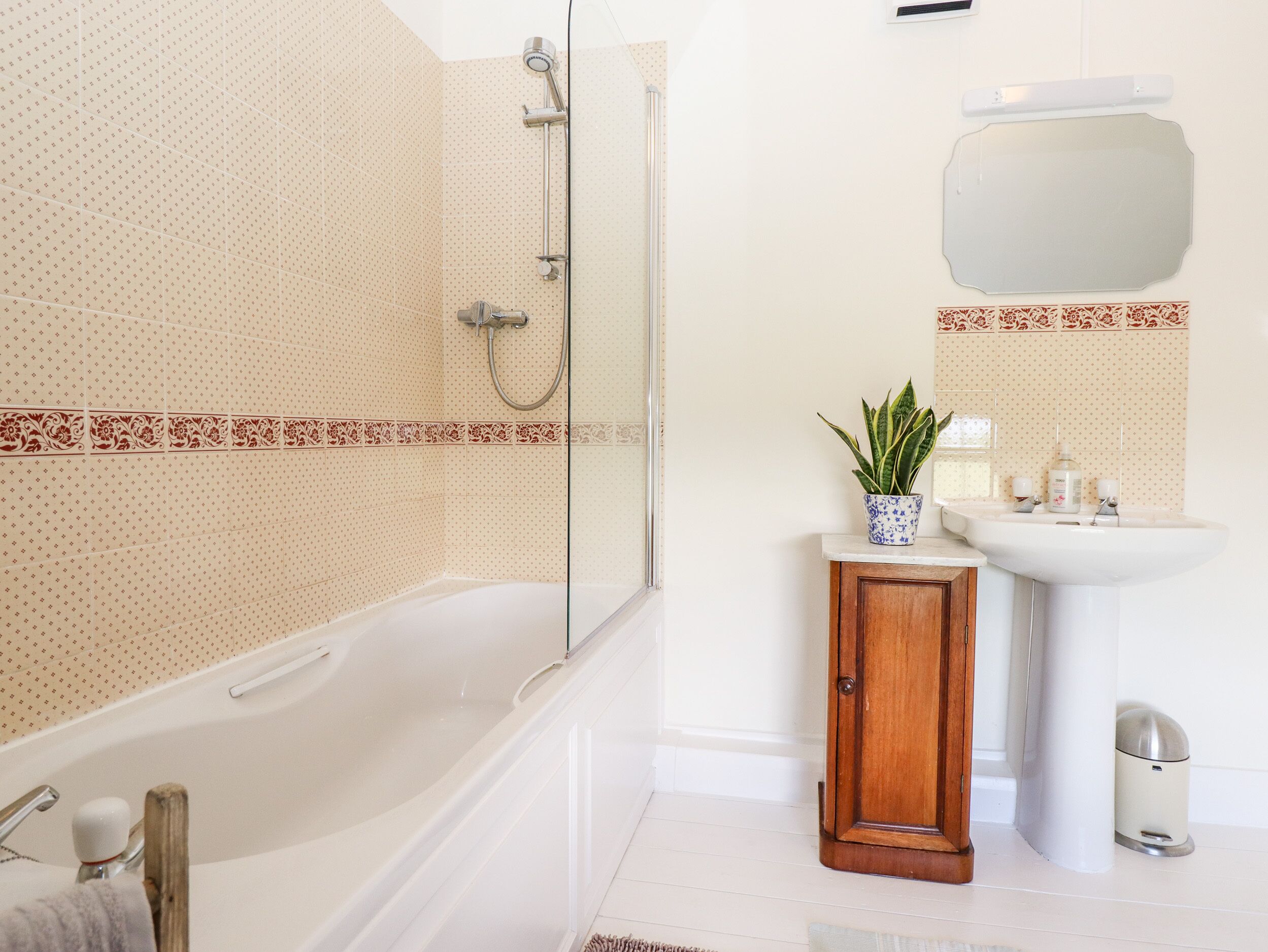 A bathroom with a bathtub, shower, sink, and a mirror.