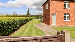 A brick house with a well-maintained lawn and a hedge. - East Farm Cottage (Lincoln)